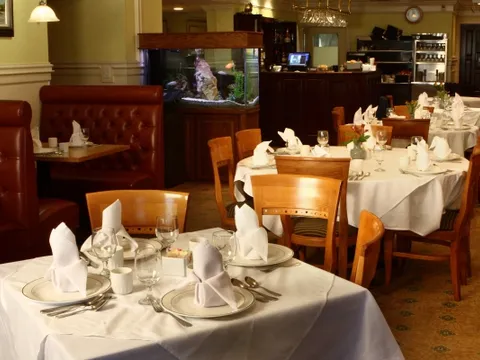 Dining room at Great Taste in New Britain with white-linen tables, red leather booths, and a built-in aquarium