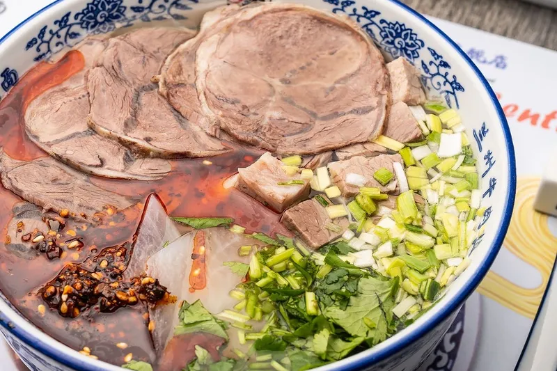 Bowl of Lanzhou hand-pulled beef noodle soup on a Lan Noodle placemat