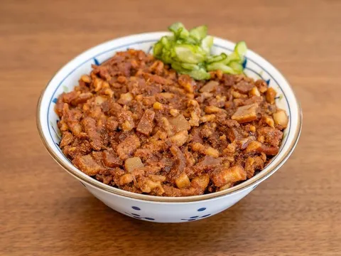 Bowl of Liu's Cafe braised pork belly rice with pickled cucumber