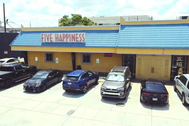 Storefront of Five Happiness (五福) at 3605 S Carrollton Ave, New Orleans — a yellow building with a blue tile roof, lion statue, and lit OPEN sign above the parking lot