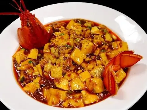 Signature Sichuan mapo-style tofu in red chili-oil sauce topped with lobster, plated on a white dish at Chuan Jiang Hao Zi in Columbus