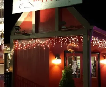Nighttime storefront of Happy China in Durham, with its 'Happy China - Sichuan cuisine' sign over a red-painted entrance strung with icicle lights and a gold lantern