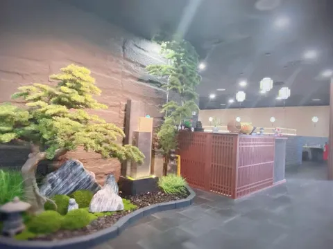 Interior of Hiya Chili in Tulsa, with a bonsai-and-rock garden feature beside a red lattice host counter under hanging Chinese lanterns
