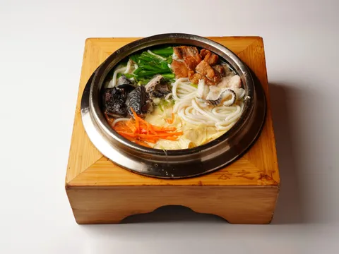 Yunnan crossing-the-bridge rice noodles served in a metal bowl on a branded wooden stand at South of the Clouds (云之南), Greenwich Village