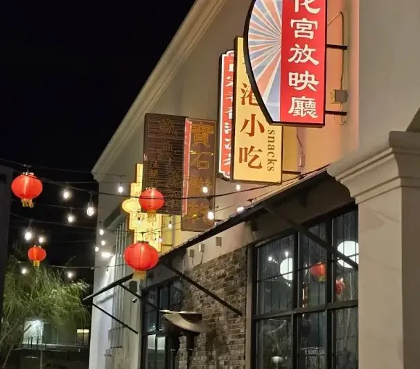 Illuminated storefront of China Town in El Paso at night, with Chinese neon signage, red lanterns and string lights over the patio