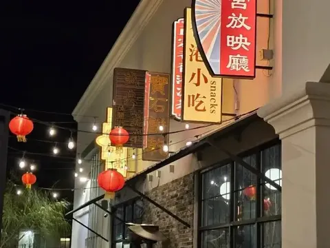 Illuminated storefront of China Town in El Paso at night, with Chinese neon signage, red lanterns and string lights over the patio